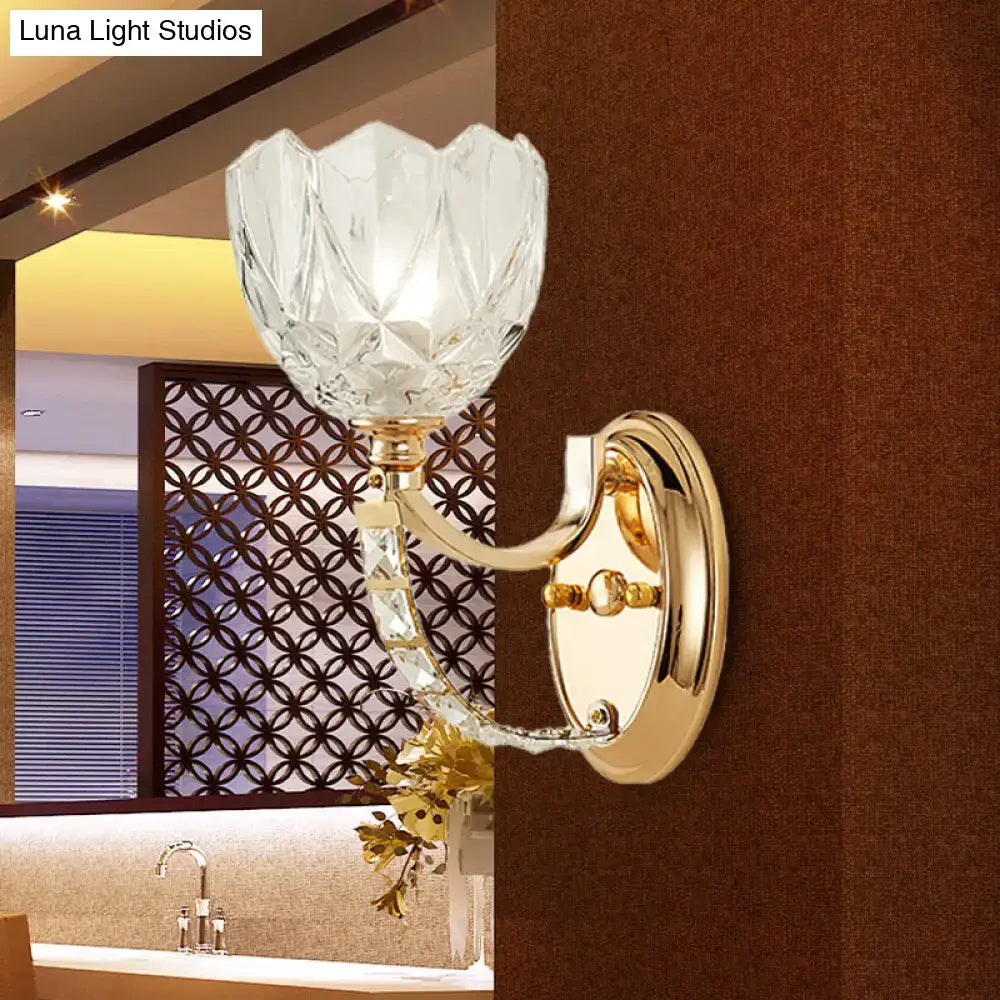 Elegant modern brass wall sconce with a gold finish and faceted clear glass shade for bedroom lighting