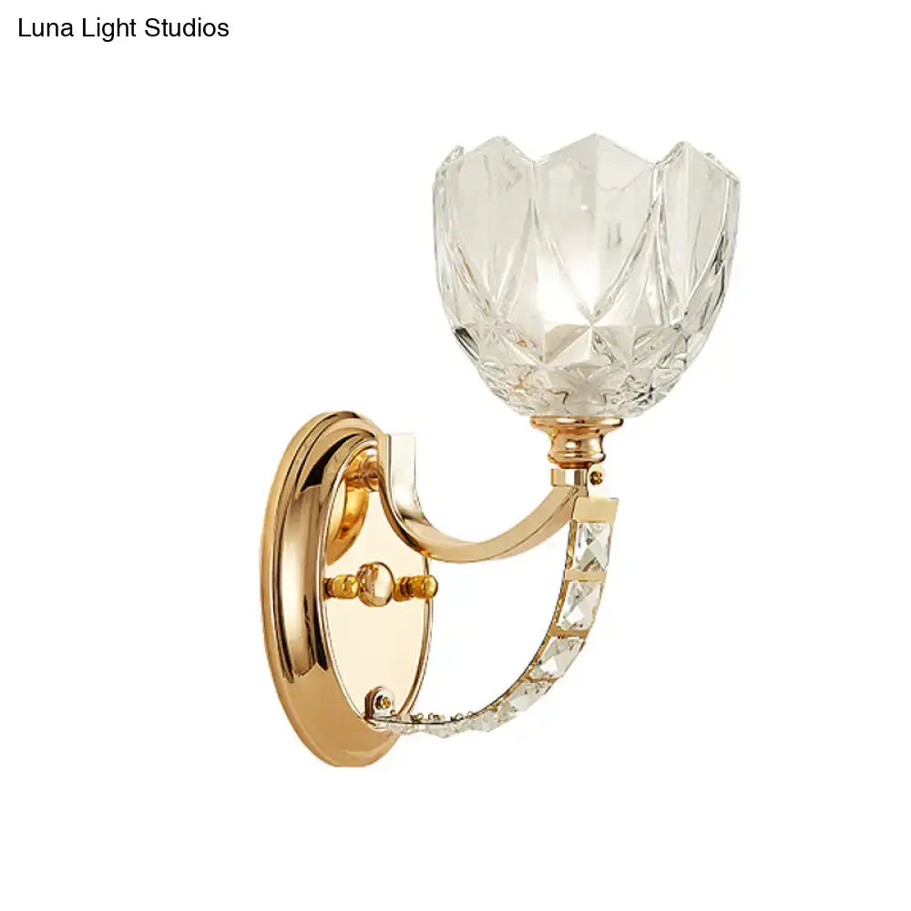 Modern brass wall sconce with elegant gold finish featuring a faceted clear glass shade and crystal-embellished arm