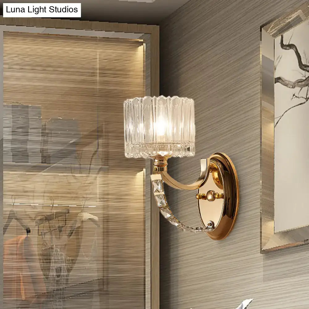 Elegant modern brass wall sconce with gold tone and faceted clear glass shade featuring decorative crystal accents