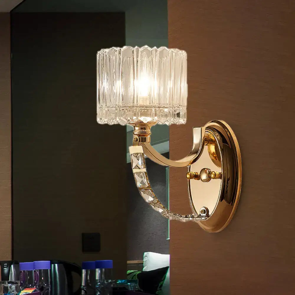 Modern brass wall sconce with gold tone and decorative crystal accents featuring a faceted clear glass shade