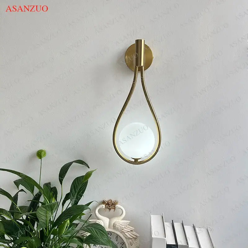 Modern brass wall sconce with gold-toned teardrop design and frosted glass globe for living room decorbites brass wall sconce
