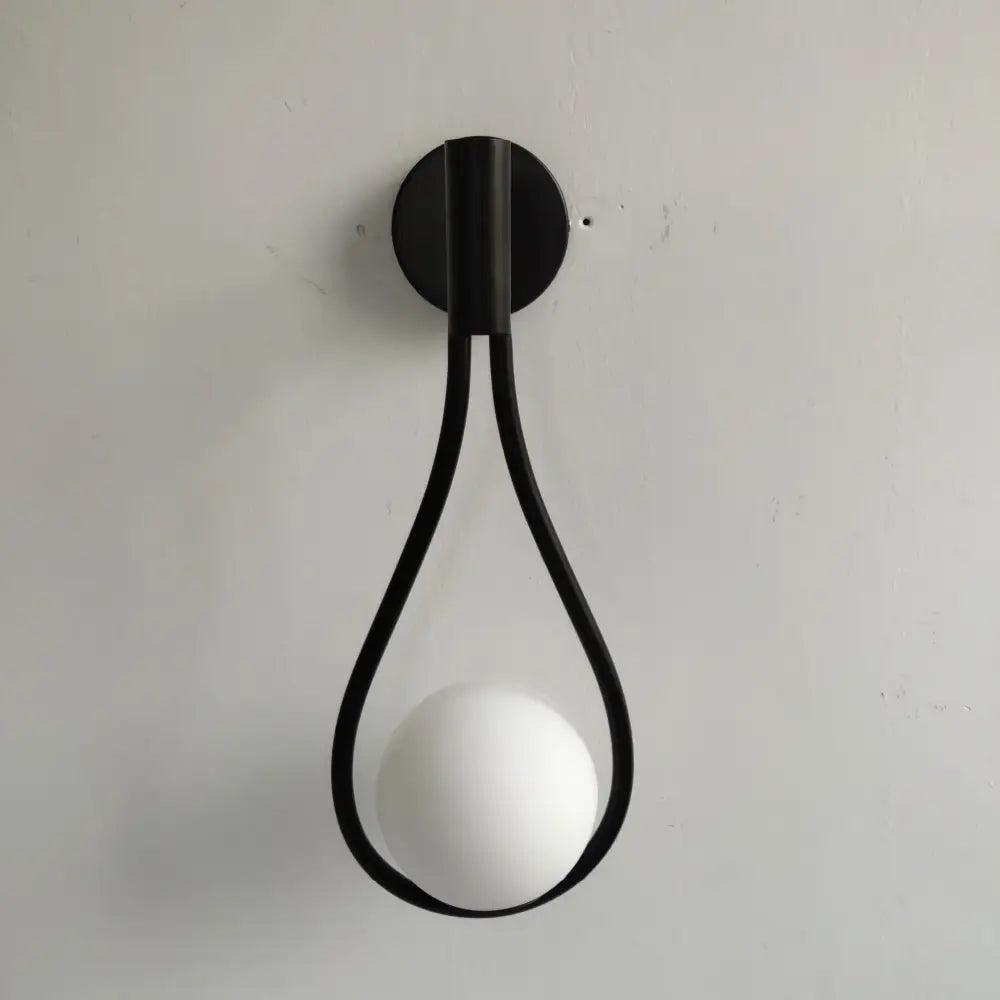 Black metal wall sconce with sleek teardrop frame and smooth white bulb as brass wall sconce decorbites living room light