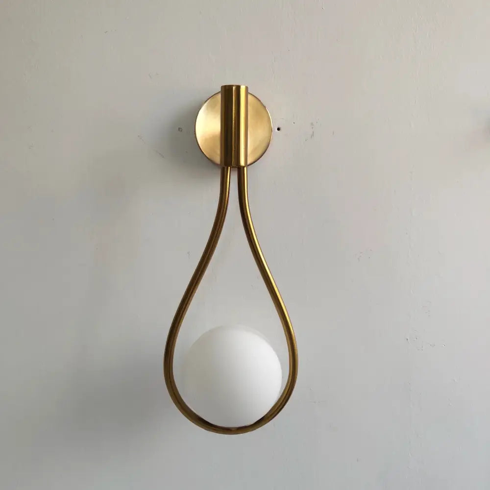 Modern brass wall sconce with gold-toned teardrop frame and frosted glass shade for living room decorbites brass wall sconce
