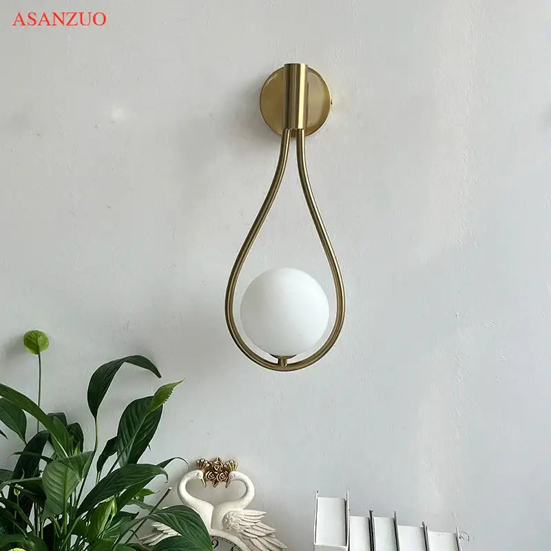 Modern brass wall sconce with a gold-toned teardrop metal frame and frosted white glass shade for living room decorbites brass wall sconce