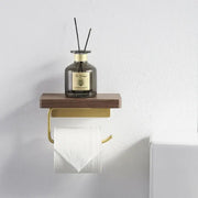 Modern brass and wood toilet paper holder with gold-toned wall-mounted paper holder and wooden shelf with diffuser bottle