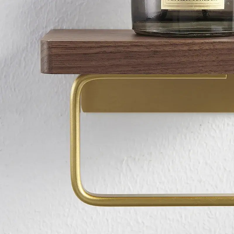 Modern brass and wood toilet paper holder with gold-toned metal paper holder mounted beneath dark wood shelf