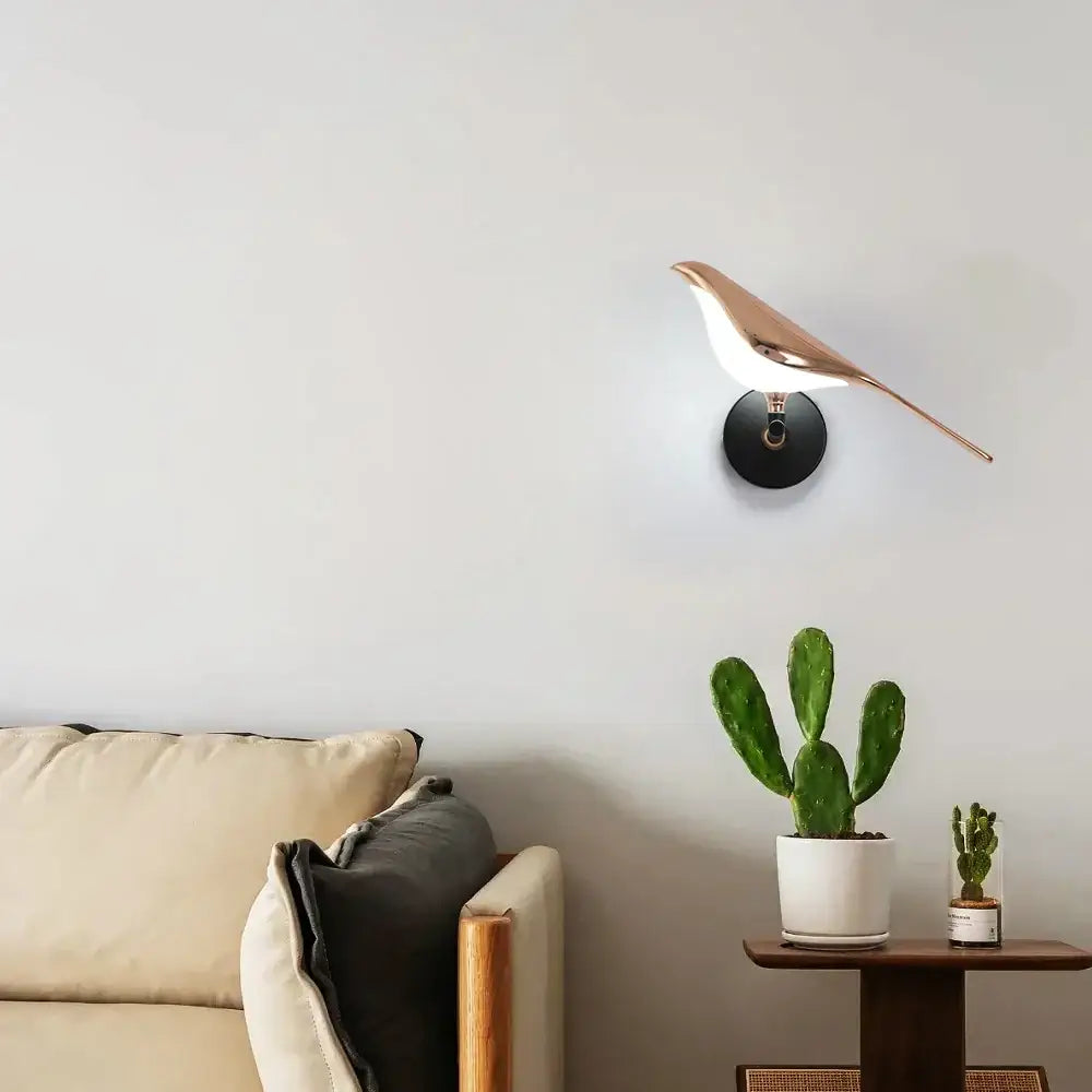 A sleek rose gold decorbites bird wall light with white interior glass and black circular base for modern wall light decor