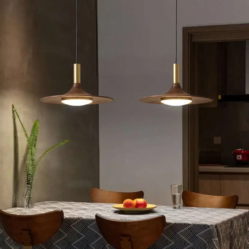 Two modern bronze black walnut ufo pendant lights with brass stems hang above a dining table decorbites black walnut
