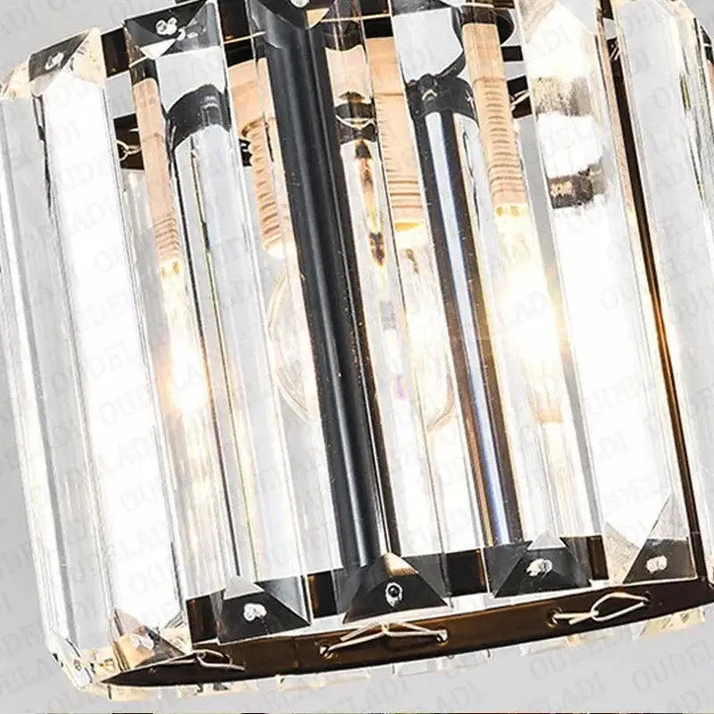 A modern bronze crystal trio pendant light featuring vertical faceted glass rods in a black metal frame for dining rooms
