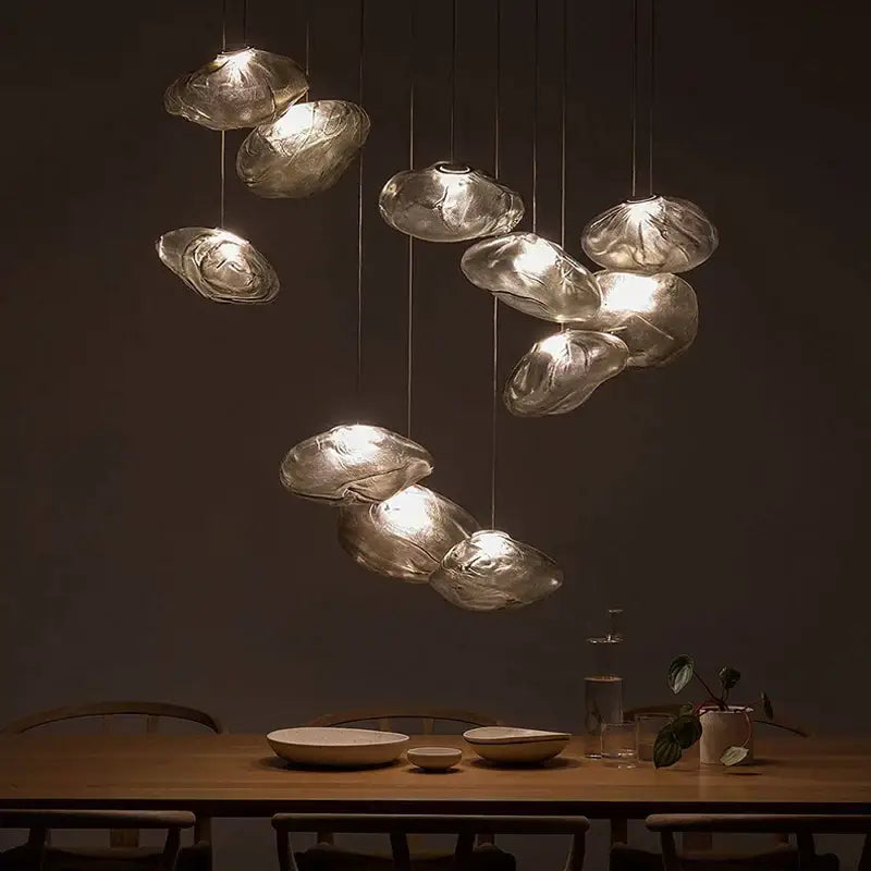 A modern bronze glass cloud chandelier pendant lamp with translucent frosted glass shades above a wooden table