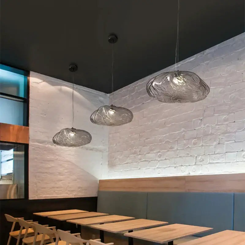 Three translucent bronze glass cloud pendant lamps hang from the ceiling in a modern glass cloud chandelier design