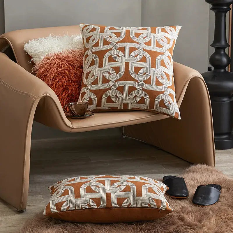 Orange and white geometric-patterned cushion cover with woven texture on tan leather chair for decorbites brown coffee decor