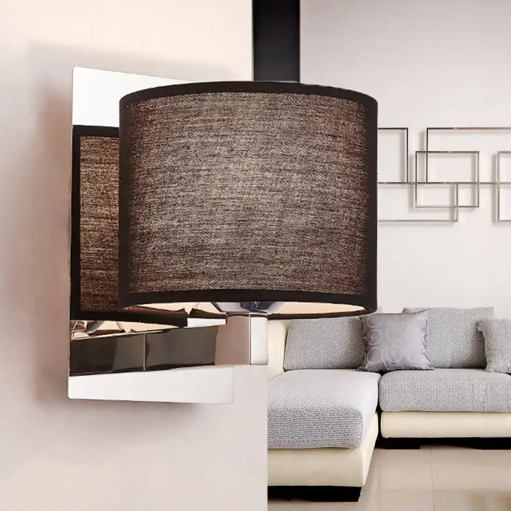 Modern brown fabric wall mount sconce with textured cylindrical lampshade and black trim on white fixture