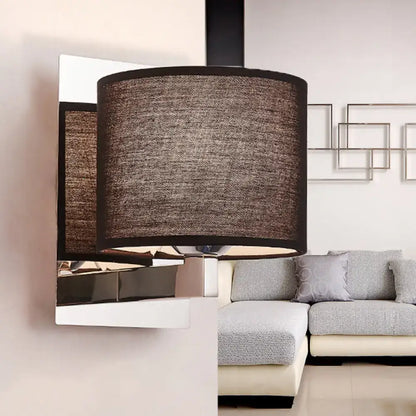 Modern brown fabric wall mount sconce with textured cylindrical lampshade and black trim on white fixture