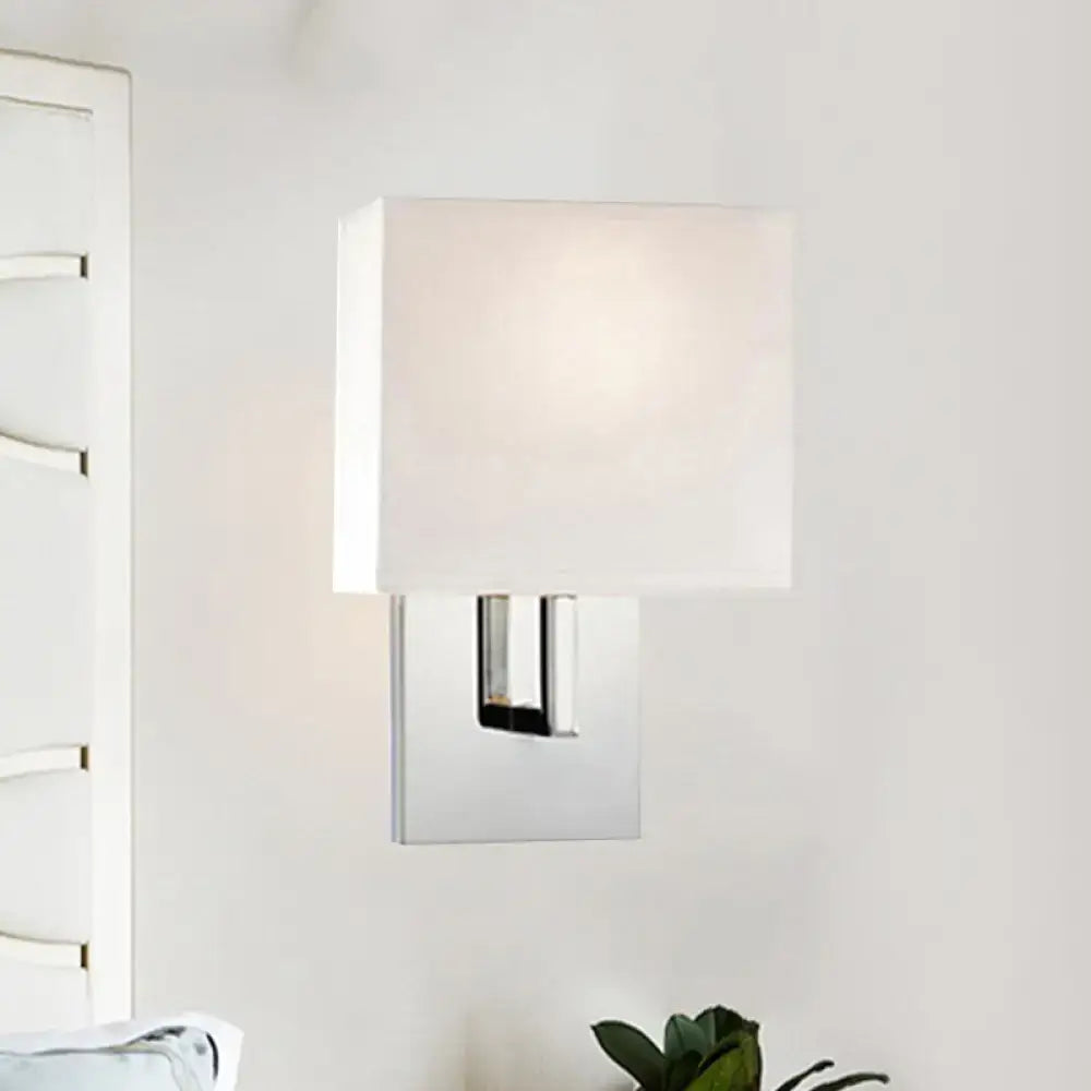 Modern brown fabric wall mount sconce with a white fabric shade and chrome metal base for bedroom use