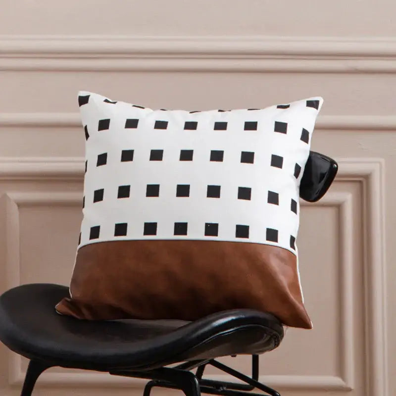 A modern brown faux leather and geometric pillow cover with black and white squares on a stylish chair decorbites brown faux