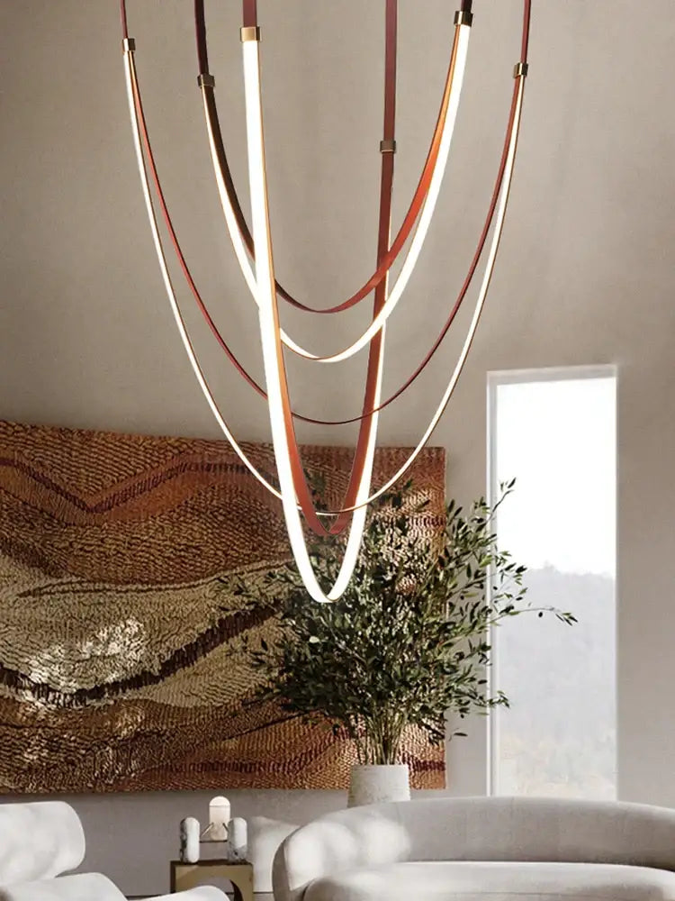 Modern chandelier with curved illuminated led strips and leather-like bands in warm brown and cream for dining room decorbites designer belt light