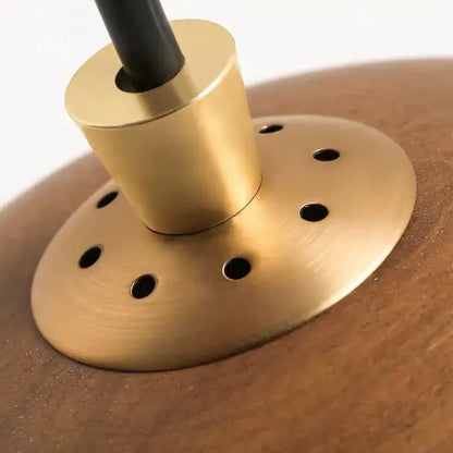 Brass-finished circular lamp base with holes and central stem for modern brown finish pendant light kitchen island design