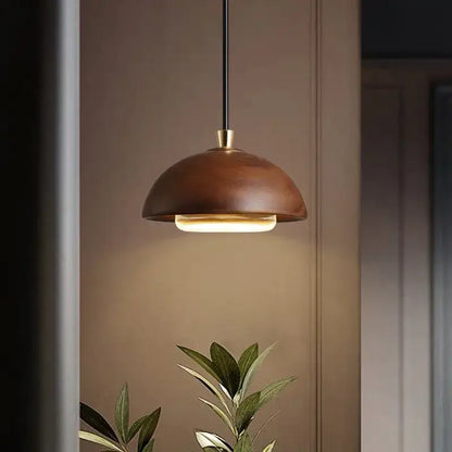 Warm-toned brass pendant light with brown finish and minimalist dome design for modern kitchen island lighting