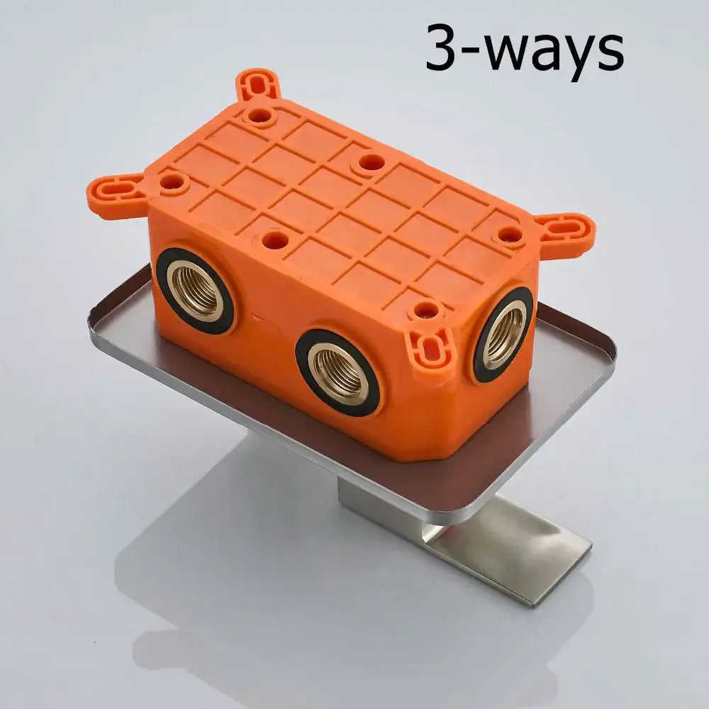 Orange plastic 3-way plumbing fitting with brass threaded ports and black seals for modern shower mixer valve use