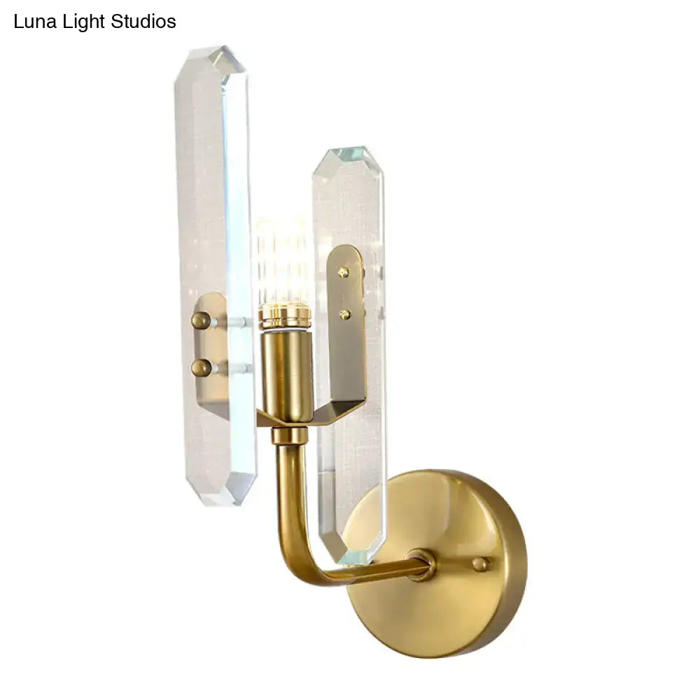 Modern brushed brass sconce light with two clear faceted crystal shade panels for elegant living room decor