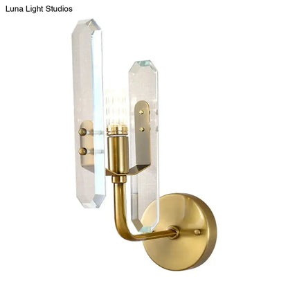 Modern brushed brass sconce light with two clear faceted crystal shade panels for elegant living room decor