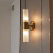 A modern brushed brass crystal wall lamp with a textured translucent glass cylinder for bedroom decorbites wall lamp
