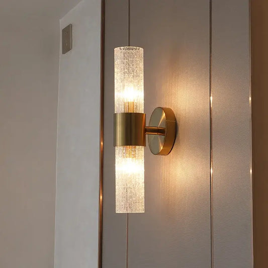 A modern brushed brass crystal wall lamp with a textured translucent glass cylinder for bedroom decorbites wall lamp