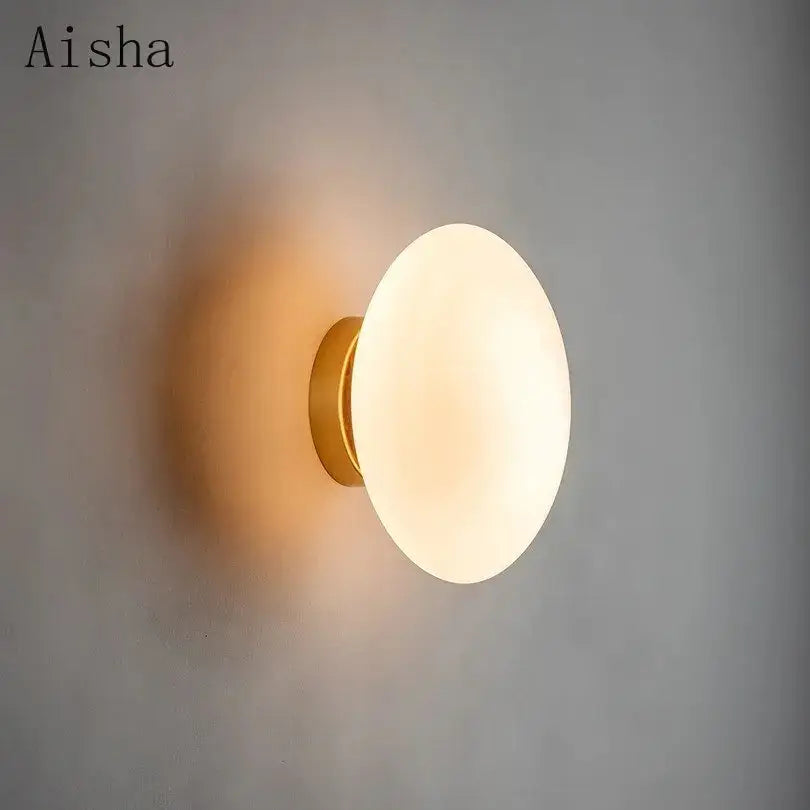 Aisha brand wall lamp with warm frosted glass disc and gold-toned metal base from decorbites golden glass ball collection