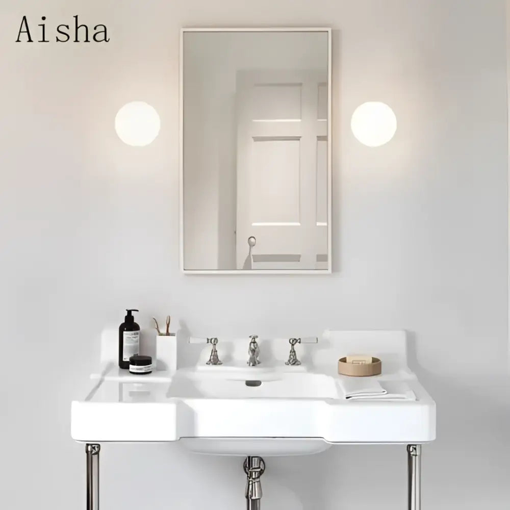 White ceramic pedestal sink with chrome legs paired with decorbites golden glass wall lamps featuring golden glass ball design