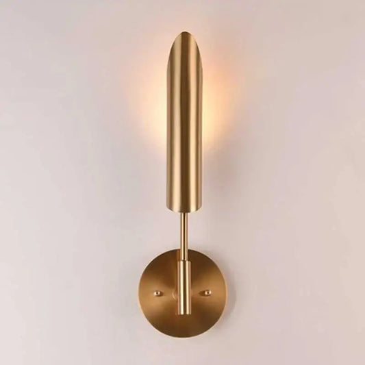 A sleek brushed brass wall lamp with a slender cylindrical shade and circular base for decorbites golden wall decor