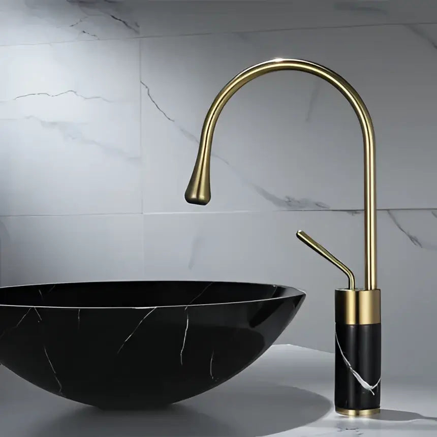 Black marble bowl sink with a brushed gold brass curved faucet featuring a modern, sleek bathroom design