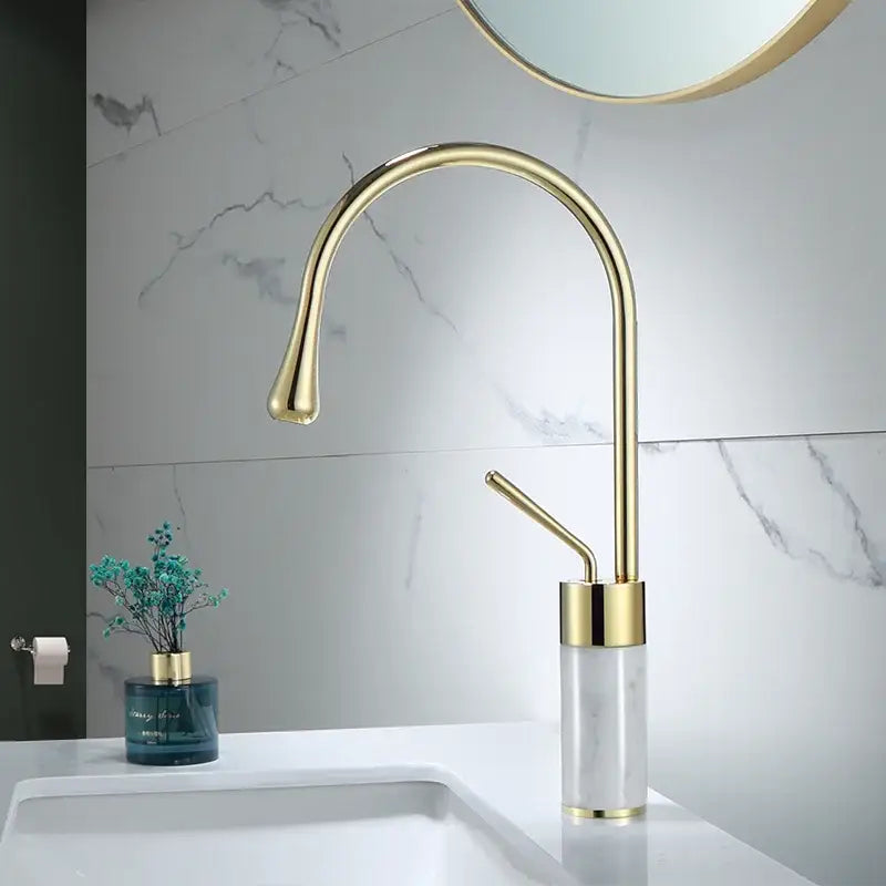 Modern bathroom sink faucet in brushed gold brass with a curved spout and marble base for stylish use