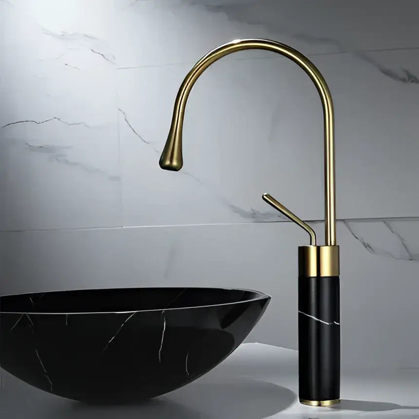 Modern brushed gold and marble bathroom sink faucet with a sleek curved spout in brushed gold brass and black marble base