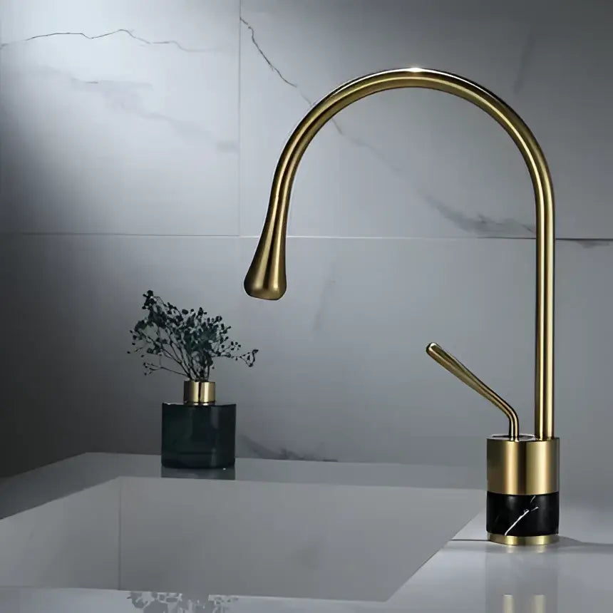 Modern brushed gold bathroom sink faucet with sleek curved spout and black marble base in brushed gold brass finish