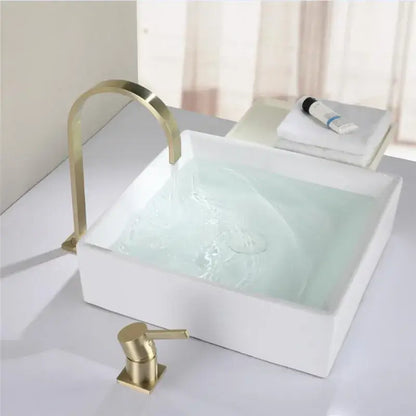 Modern brushed gold basin faucet with a sleek curved spout and soap dispenser paired with a white ceramic sink decorbites brushed gold