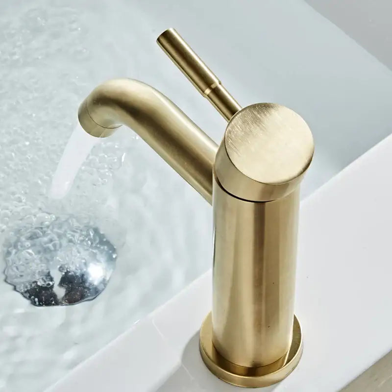 A sleek modern brushed gold basin faucet with a cylindrical single handle design for bathroom use by decorbites
