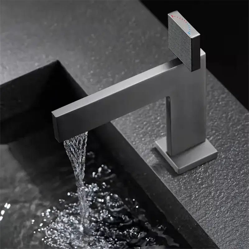 Modern matte black basin faucet with square textured control knob complements decorbites brushed gold bathroom design