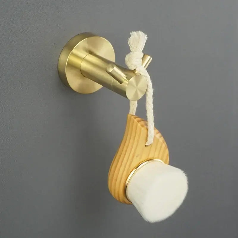 A golden brass wall-mounted hook with natural wood and white sponge in a modern brushed gold bath hardware set