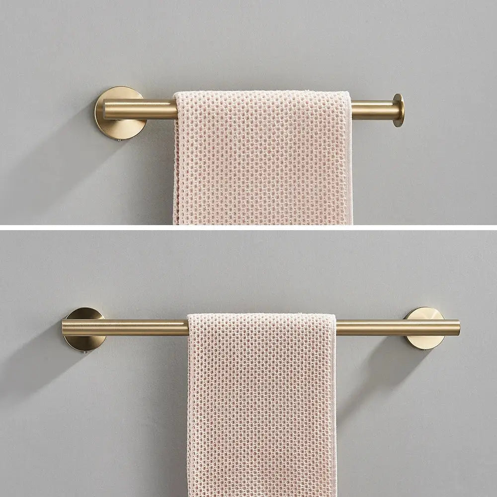 Modern brushed gold wall-mounted towel rack holding a pale pink textured towel in stainless steel bathroom accessories set