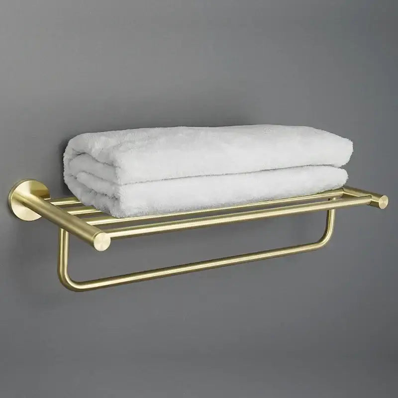 Modern brushed gold bathroom hardware set featuring a sleek towel rack with neatly folded white towels