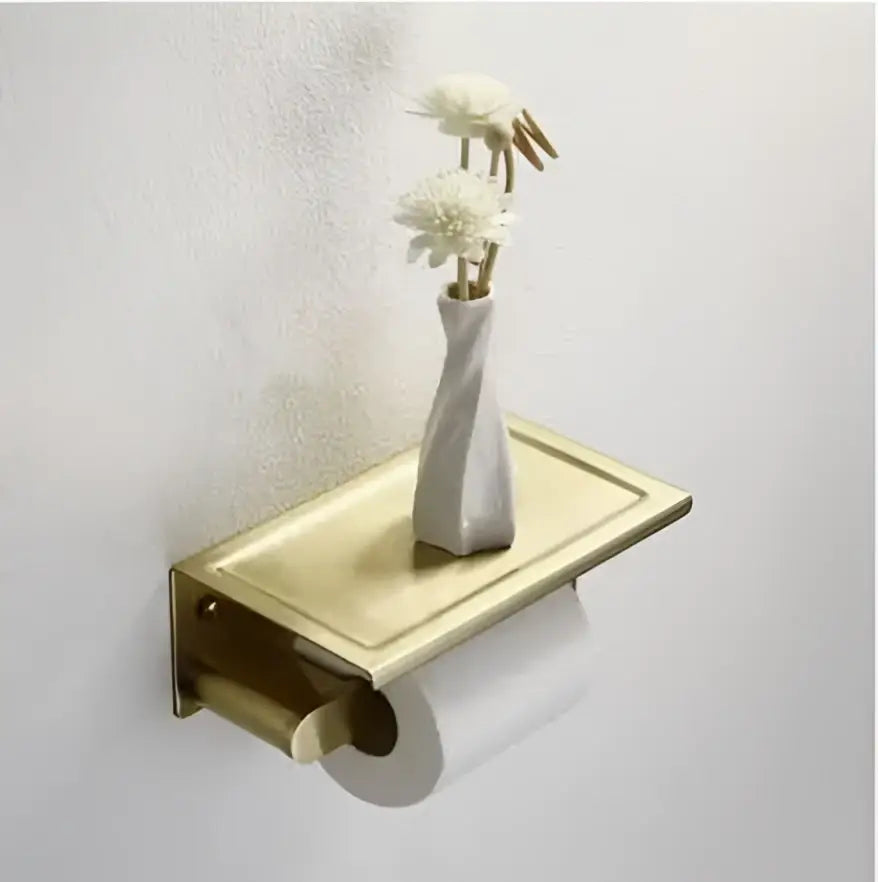 Gold-toned wall-mounted toilet paper holder with rectangular shelf and white vase from decorbites brushed gold hardware set