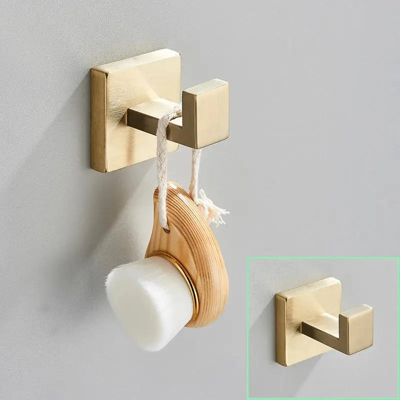 Modern brushed gold hardware set with square brackets featuring a gold-toned wall hook holding a wooden and white brush