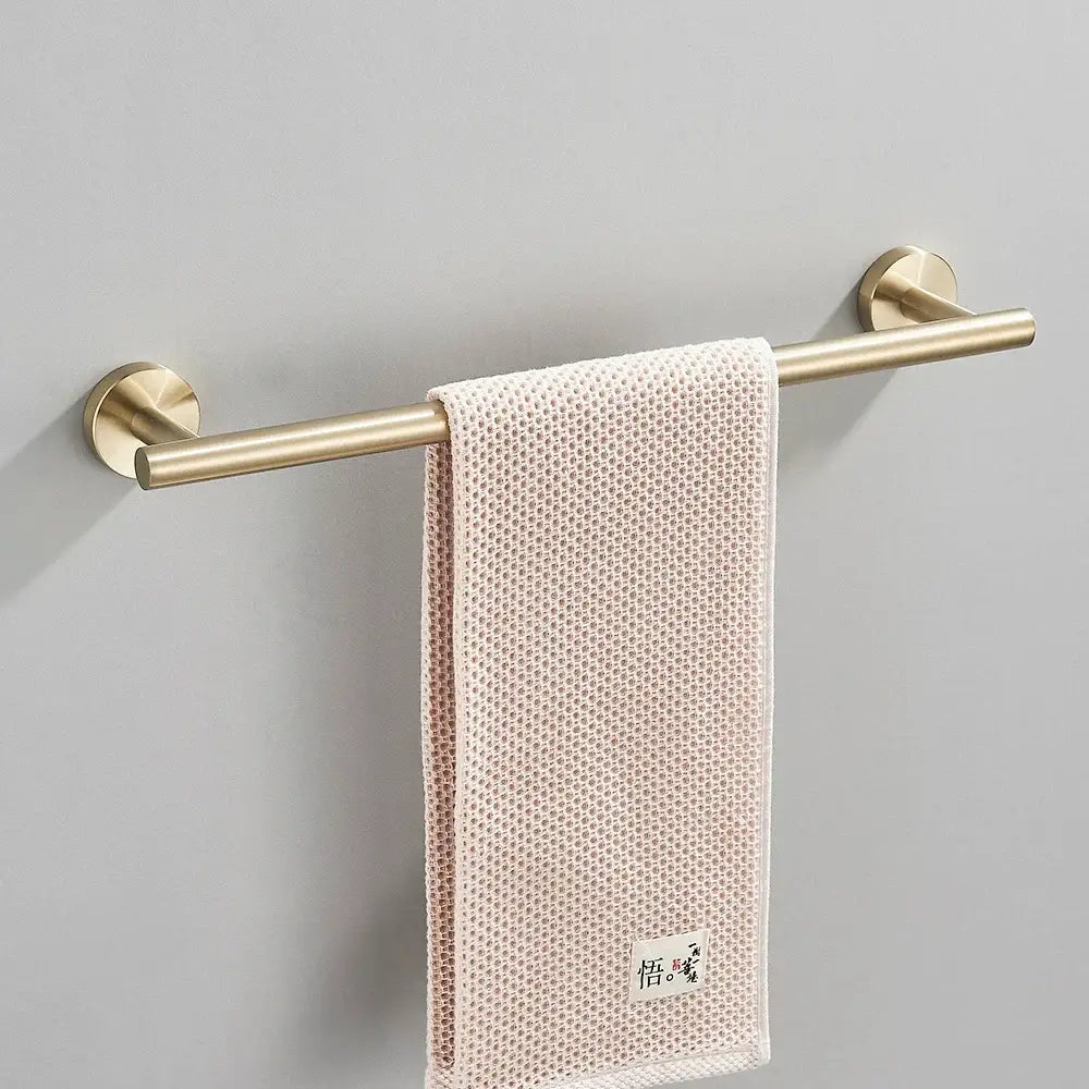 Modern brushed gold bathroom hardware set with towel bar featuring a delicate pink textured towel on decorbites brushed gold rack