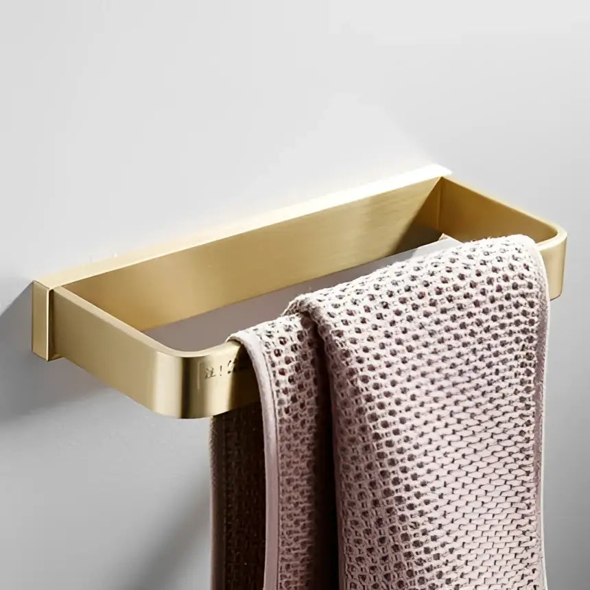 Modern brushed gold hardware set with a gold-toned rectangular towel rack holding a textured mauve towel decorbites brushed gold