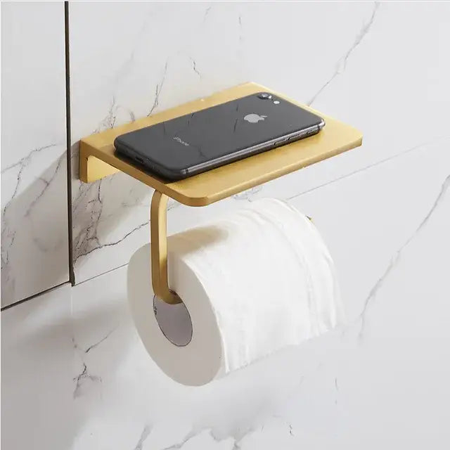 Modern brushed gold bathroom set metal toilet paper holder with integrated shelf holding black smartphone decorbites brushed gold