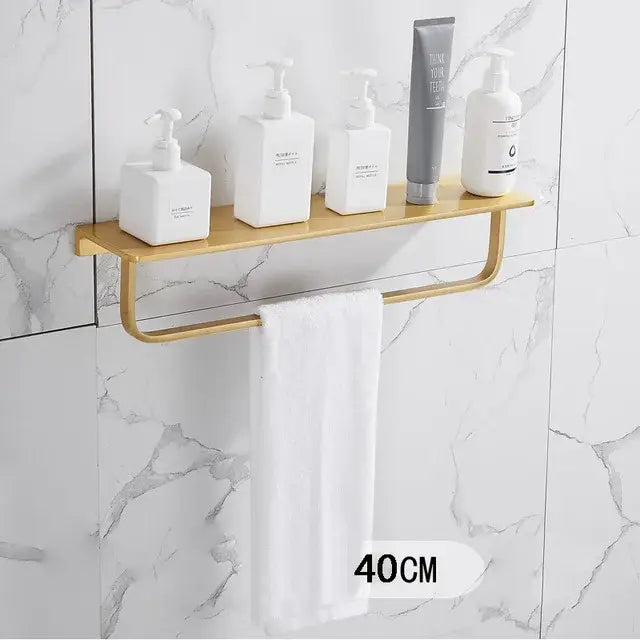 Modern brushed gold bathroom set with metal shelf and integrated towel bar holding white and gray pump bottles decorbites brushed gold