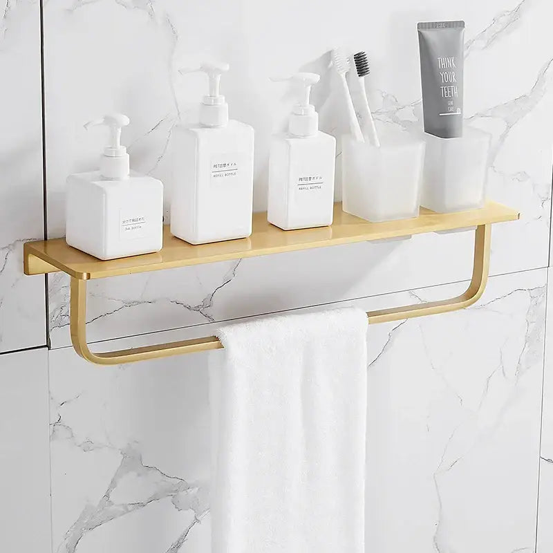 Modern brushed gold bathroom set shelf with integrated towel bar holding white toiletries decorbites brushed gold
