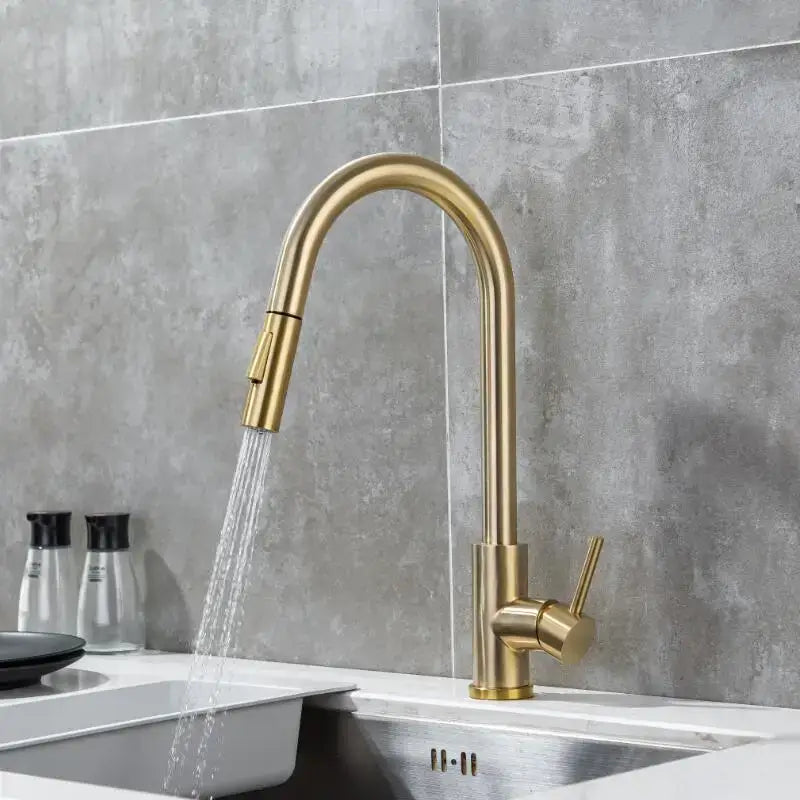 Modern brushed gold and black kitchen faucet with pull out hose featuring a curved spout and pull down spray head