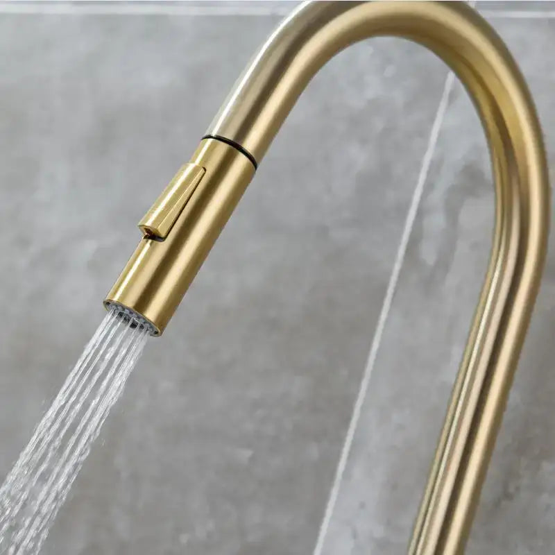 Modern brushed gold and black kitchen faucet with pull out hose featuring a gold-toned curved spout decorbites brushed gold